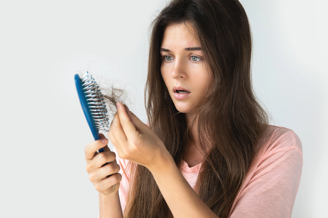 אישה מוציאה שיערות מהמברשת שלה בגלל נשירת שיער
